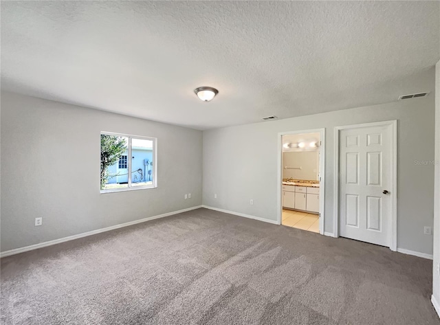 10350 SW 62nd Terrace Rd, Ocala, FL 34476 - unfurnished bedroom with light colored carpet, a textured ceiling, baseboards, and ensuite bath