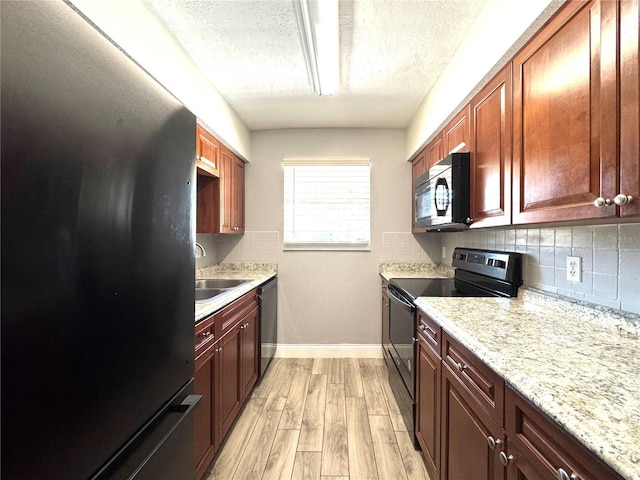 kitchen with black appliances, a sink, a textured ceiling, decorative backsplash, and baseboards