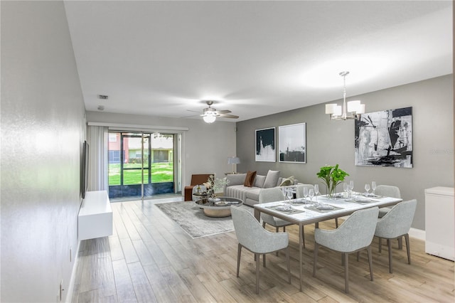 dining area featuring a chandelier, wood finished floors, a ceiling fan, and baseboards