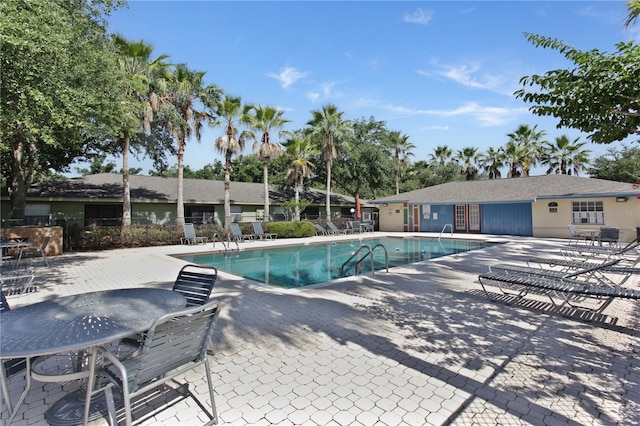 community pool with a patio area and fence