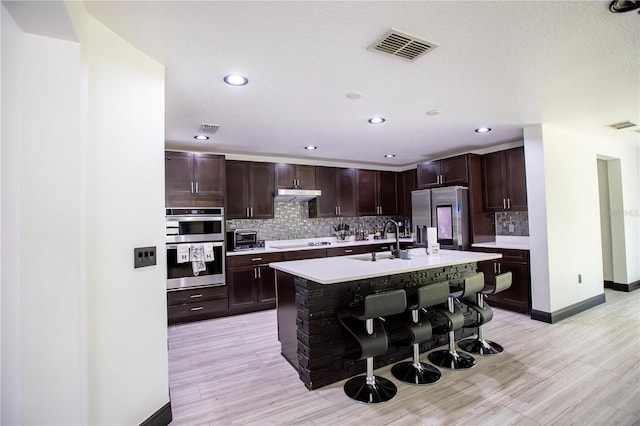 13851 Rushing Creek Run, Orlando, FL 32824 - kitchen with appliances with stainless steel finishes, a sink, light countertops, a breakfast bar area, and backsplash
