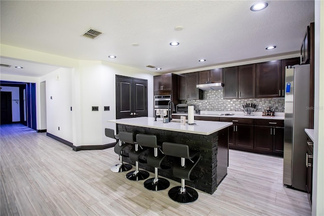 13851 Rushing Creek Run, Orlando, FL 32824 - kitchen with freestanding refrigerator, a kitchen bar, light countertops, under cabinet range hood, and baseboards