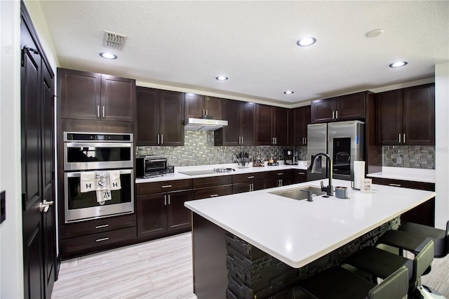 13851 Rushing Creek Run, Orlando, FL 32824 - kitchen with appliances with stainless steel finishes, a sink, under cabinet range hood, light countertops, and recessed lighting