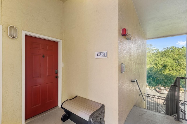 view of exterior entry with stucco siding and a balcony