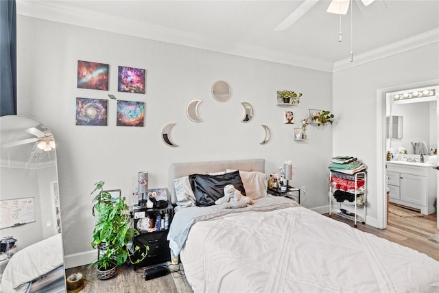 bedroom featuring ornamental molding, wood finished floors, ensuite bath, baseboards, and ceiling fan