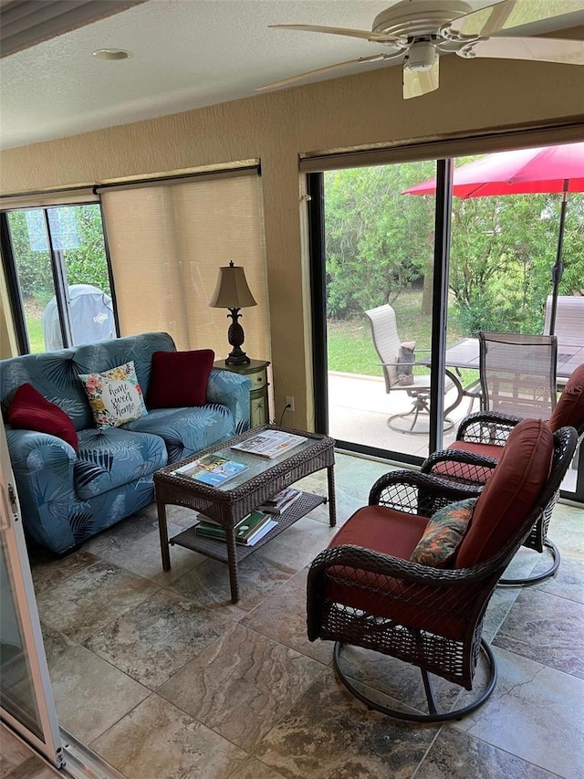 1121 Alcove Loop, The Villages, FL 32162 - living area featuring stone tile floors, healthy amount of natural light, and a ceiling fan