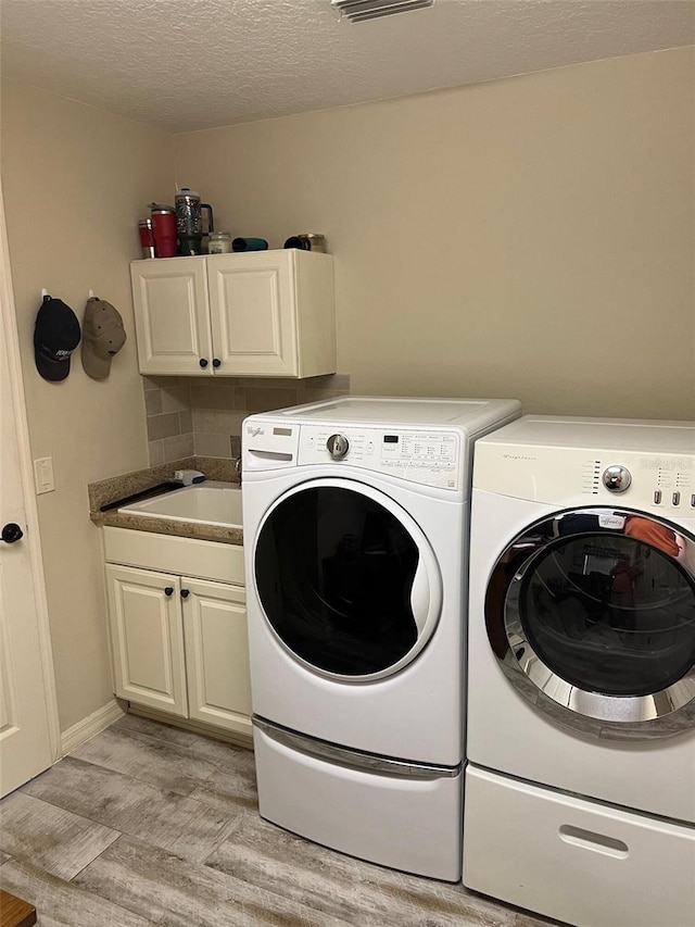 1121 Alcove Loop, The Villages, FL 32162 - clothes washing area featuring independent washer and dryer, cabinet space, light wood-style floors, and a textured ceiling