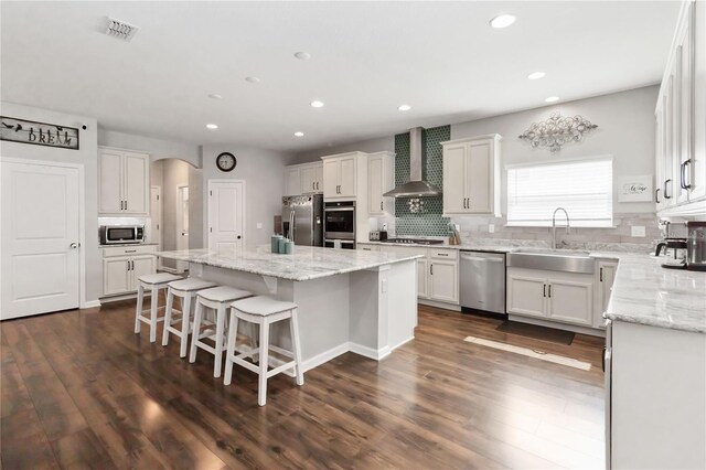 1265 Blarney St, Minneola, FL 34715 - kitchen with wall chimney exhaust hood, appliances with stainless steel finishes, a sink, a center island, and tasteful backsplash