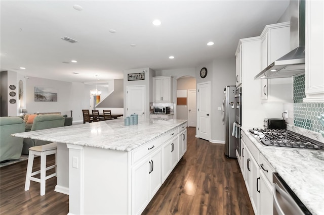 1265 Blarney St, Minneola, FL 34715 - kitchen with wall chimney range hood, stainless steel appliances, a large island, open floor plan, and white cabinets