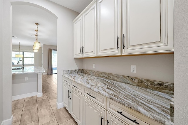 3844 Bowfin Trl, Kissimmee, FL 34746 - kitchen with a sink, white cabinets, baseboards, decorative light fixtures, and light stone countertops