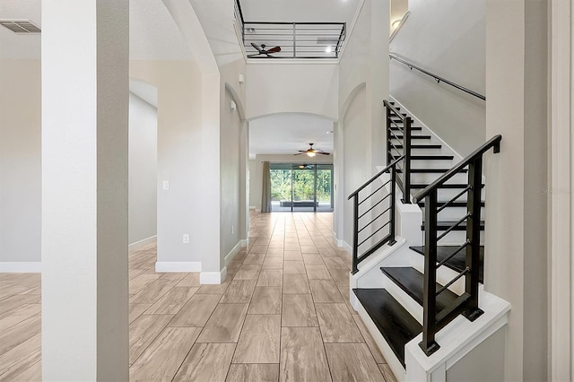 3844 Bowfin Trl, Kissimmee, FL 34746 - foyer entrance with a ceiling fan, arched walkways, stairs, wood tiled floors, and a towering ceiling
