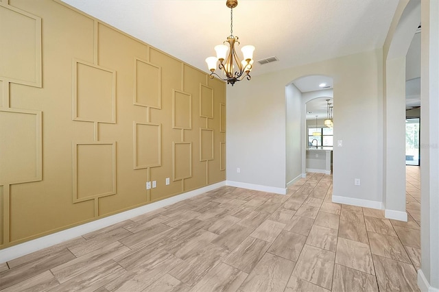 3844 Bowfin Trl, Kissimmee, FL 34746 - unfurnished room with arched walkways, a chandelier, healthy amount of natural light, and baseboards