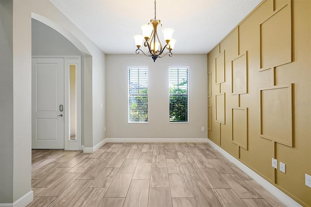 3844 Bowfin Trl, Kissimmee, FL 34746 - unfurnished room with a chandelier, arched walkways, wood tiled floors, and baseboards