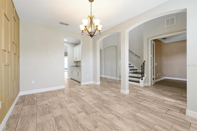 3844 Bowfin Trl, Kissimmee, FL 34746 - empty room with arched walkways, stairs, a chandelier, baseboards, and light wood-style flooring