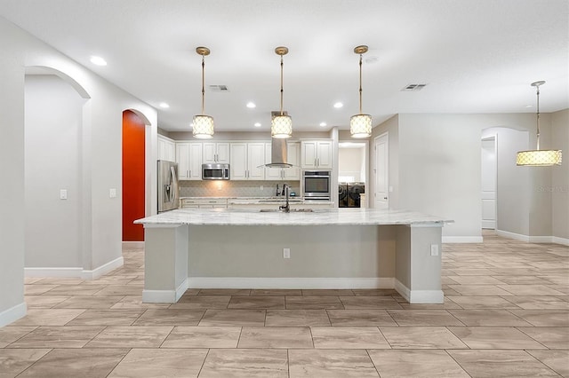 3844 Bowfin Trl, Kissimmee, FL 34746 - kitchen with appliances with stainless steel finishes, wall chimney range hood, backsplash, light stone counters, and recessed lighting