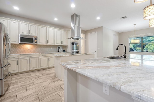 3844 Bowfin Trl, Kissimmee, FL 34746 - kitchen with appliances with stainless steel finishes, a sink, island exhaust hood, a kitchen island, and tasteful backsplash