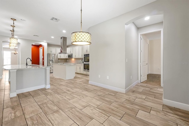 3844 Bowfin Trl, Kissimmee, FL 34746 - kitchen with a kitchen island with sink, arched walkways, island exhaust hood, a sink, and stainless steel appliances