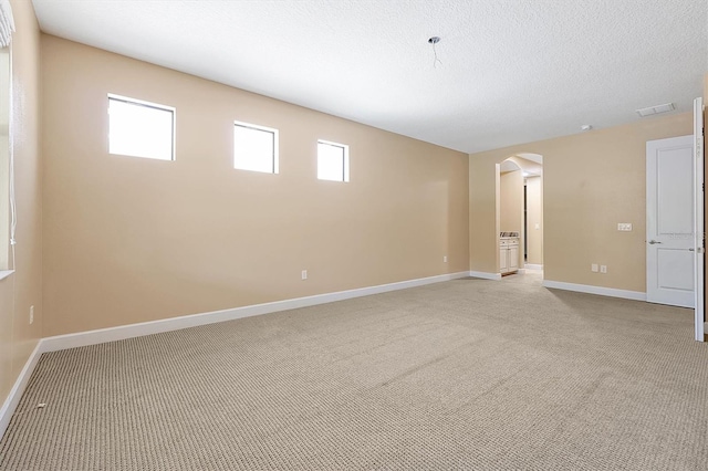 3844 Bowfin Trl, Kissimmee, FL 34746 - spare room with arched walkways, light carpet, baseboards, and a textured ceiling