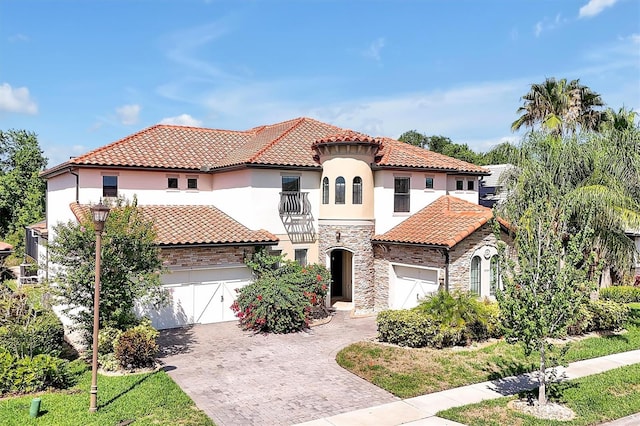 3844 Bowfin Trl, Kissimmee, FL 34746 - mediterranean / spanish-style house featuring a balcony, stone siding, stucco siding, decorative driveway, and a tile roof