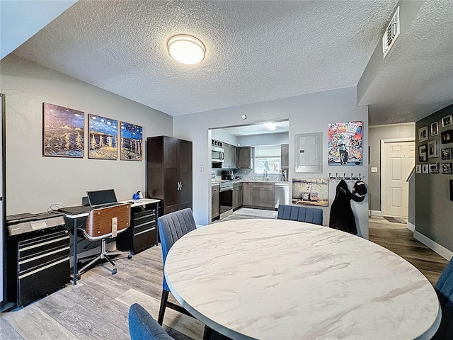 dining space featuring light wood-style floors, a textured ceiling, baseboards, and an office area