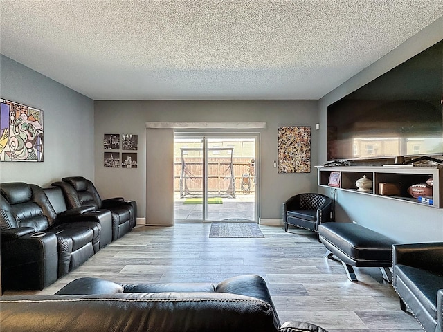 living area featuring wood finished floors, a textured ceiling, and baseboards
