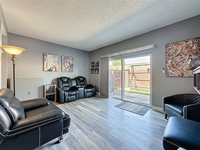 living room featuring wood finished floors, a textured ceiling, and baseboards