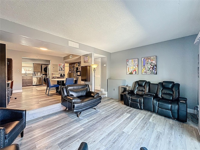 living area featuring light wood finished floors, baseboards, and a textured ceiling