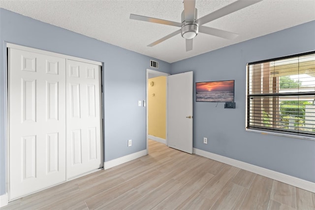 3475 Flossmoor Ave Unit 103, Orlando, FL 32822 - unfurnished bedroom featuring light wood-style flooring, baseboards, a closet, a textured ceiling, and ceiling fan