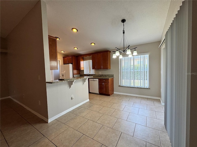 703 Tartan Loop, Lake Wales, FL 33853 - kitchen with dishwashing machine, white refrigerator with ice dispenser, a breakfast bar, light stone countertops, and a peninsula
