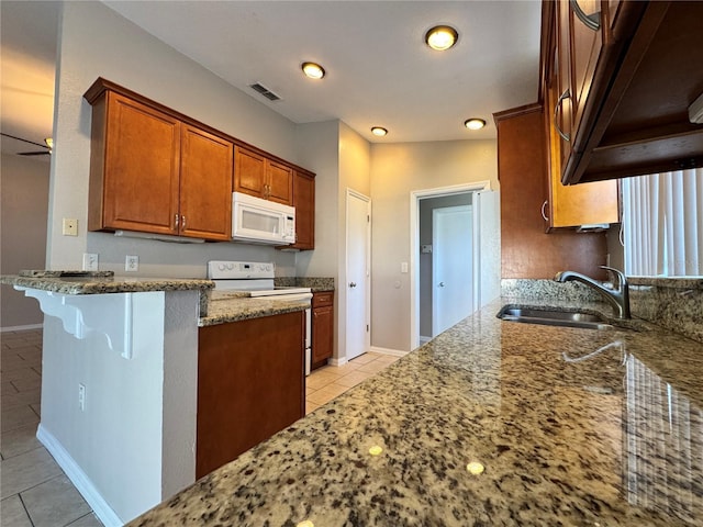 703 Tartan Loop, Lake Wales, FL 33853 - kitchen featuring white appliances, a sink, light tile patterned floors, stone counters, and brown cabinets