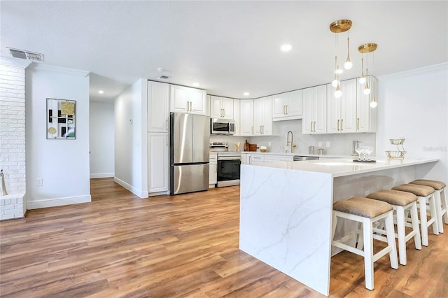 6700 Tamarind Cir, Orlando, FL 32819 - kitchen with appliances with stainless steel finishes, a peninsula, a kitchen breakfast bar, white cabinets, and crown molding
