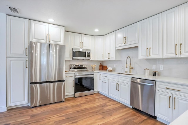6700 Tamarind Cir, Orlando, FL 32819 - kitchen featuring appliances with stainless steel finishes, a sink, white cabinets, light countertops, and recessed lighting