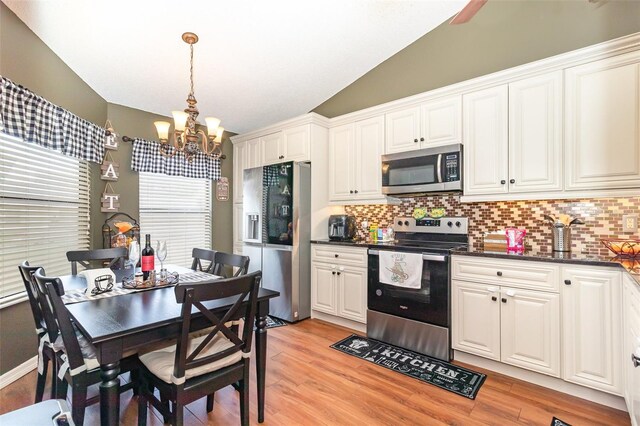 109 Lakepointe Cir, Kissimmee, FL 34743 - kitchen featuring appliances with stainless steel finishes, a chandelier, backsplash, lofted ceiling, and light wood-style floors