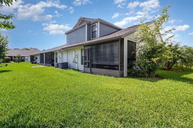 109 Lakepointe Cir, Kissimmee, FL 34743 - rear view of house featuring a sunroom, central AC unit, a yard, and roof with shingles