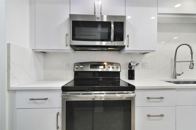 530 E Central Blvd Unit 803, Orlando, FL 32801 - kitchen with appliances with stainless steel finishes, a sink, white cabinetry, and backsplash