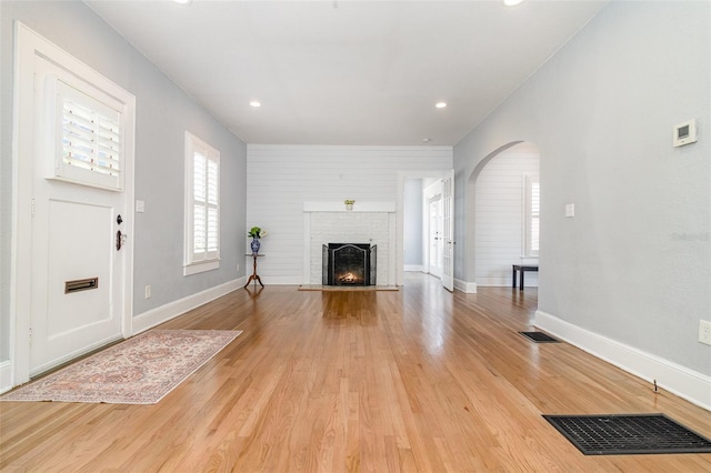 338 E Anderson St, Orlando, FL 32801 - unfurnished living room with arched walkways, a fireplace, light wood-type flooring, baseboards, and recessed lighting