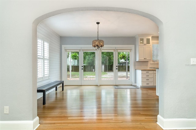 338 E Anderson St, Orlando, FL 32801 - unfurnished dining area with arched walkways, light wood-type flooring, french doors, and a chandelier