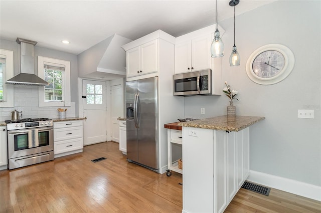 338 E Anderson St, Orlando, FL 32801 - kitchen with stainless steel appliances, wall chimney range hood, baseboards, light wood-style flooring, and white cabinets