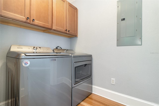 338 E Anderson St, Orlando, FL 32801 - laundry room with electric panel, washing machine and clothes dryer, cabinet space, light wood finished floors, and baseboards