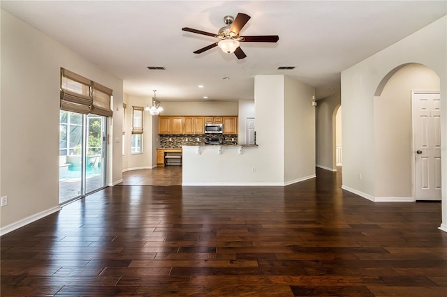 1201 Shelter Rock Rd, Orlando, FL 32835 - unfurnished living room featuring arched walkways, dark wood-type flooring, ceiling fan, baseboards, and a chandelier