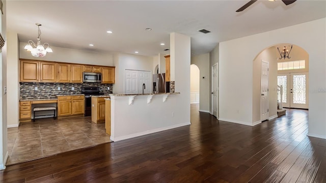 1201 Shelter Rock Rd, Orlando, FL 32835 - kitchen featuring appliances with stainless steel finishes, arched walkways, dark wood finished floors, a kitchen breakfast bar, and recessed lighting