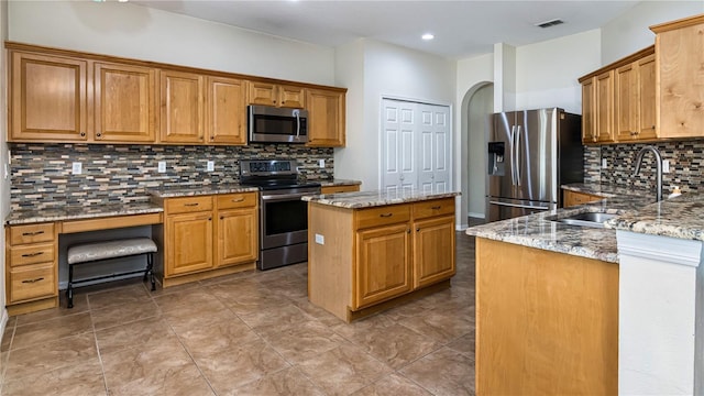 1201 Shelter Rock Rd, Orlando, FL 32835 - kitchen with stainless steel appliances, a sink, backsplash, light stone countertops, and a kitchen island