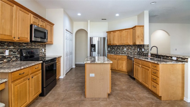 1201 Shelter Rock Rd, Orlando, FL 32835 - kitchen featuring appliances with stainless steel finishes, arched walkways, a sink, a center island, and light stone countertops