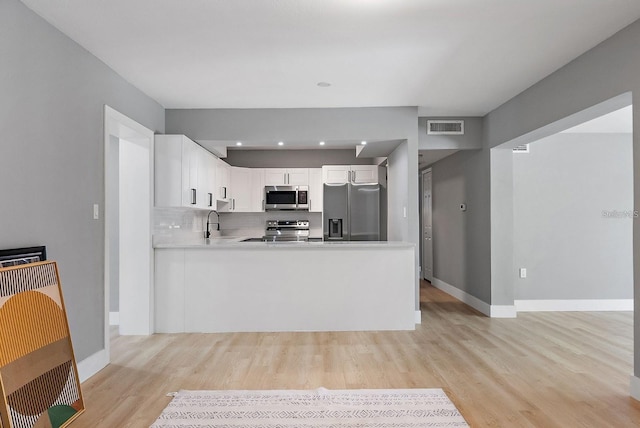 3926 Helena St NE, Saint Petersburg, FL 33703 - kitchen with appliances with stainless steel finishes, light wood-type flooring, baseboards, light countertops, and white cabinets