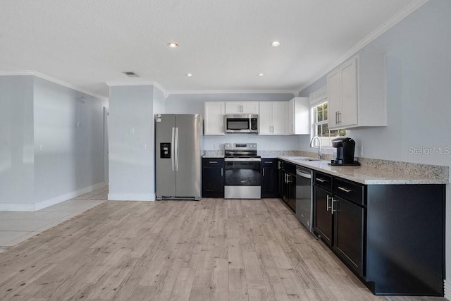 950 Gatewood Ct NE, Palm Bay, FL 32905 - kitchen with stainless steel appliances, light wood finished floors, white cabinets, dark cabinetry, and a sink