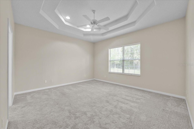 45 Powder Horn Dr, Palm Coast, FL 32164 - empty room with carpet, a ceiling fan, a tray ceiling, baseboards, and a textured ceiling