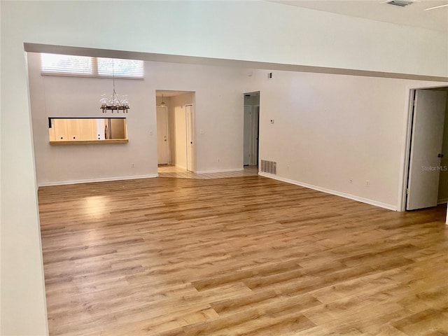 650 Woodridge Dr, Fern Park, FL 32730 - unfurnished room with light wood-style flooring, a chandelier, baseboards, and a high ceiling