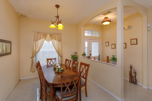 dining space with arched walkways, light tile patterned floors, baseboards, and a chandelier
