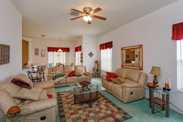 carpeted living area with ceiling fan and arched walkways