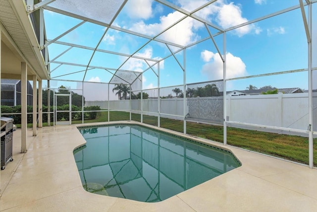 view of swimming pool featuring a patio area, glass enclosure, and fence